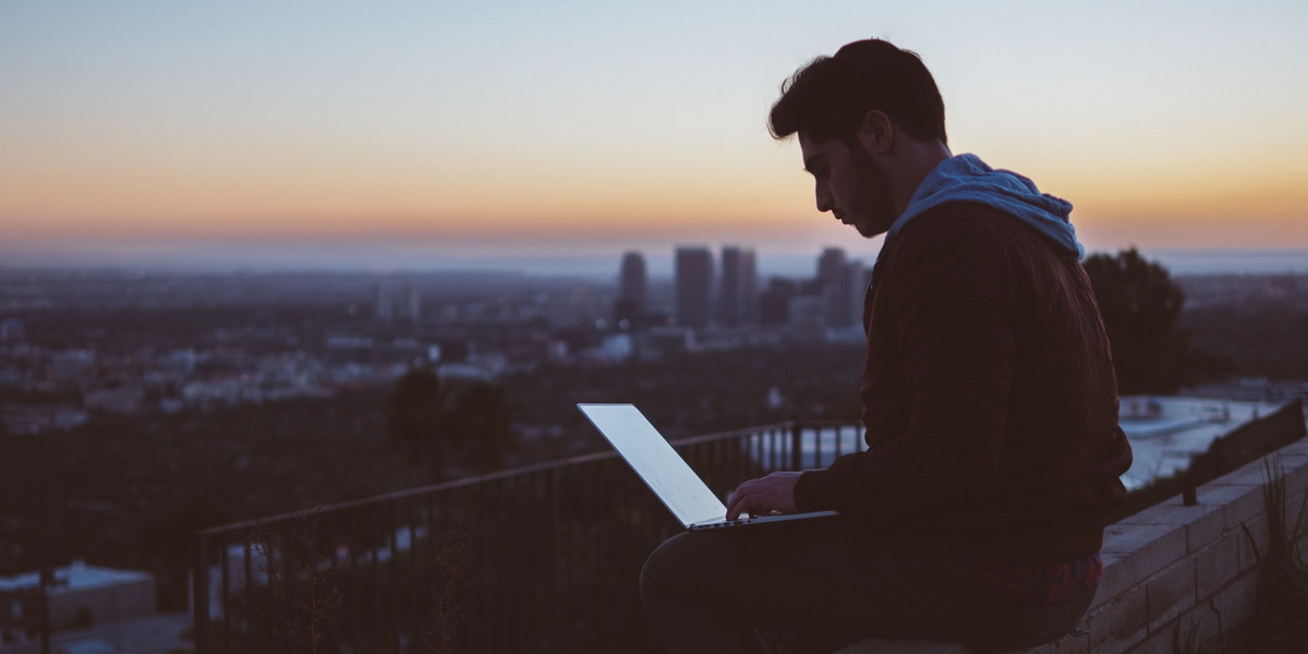 Ein Mann mit Laptop sitzt im Freien und arbeitet