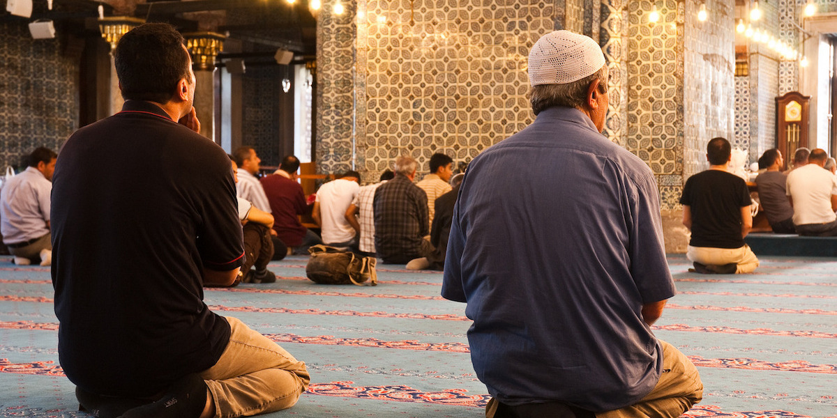 Personen beten auf den Knien in einer Moschee