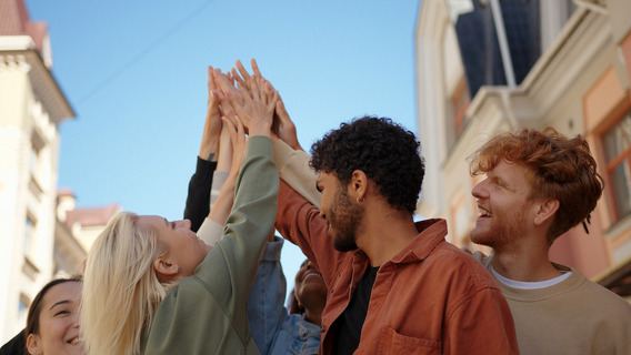 Eine Gruppe junger Menschen schlägt die Hände zusammen.
