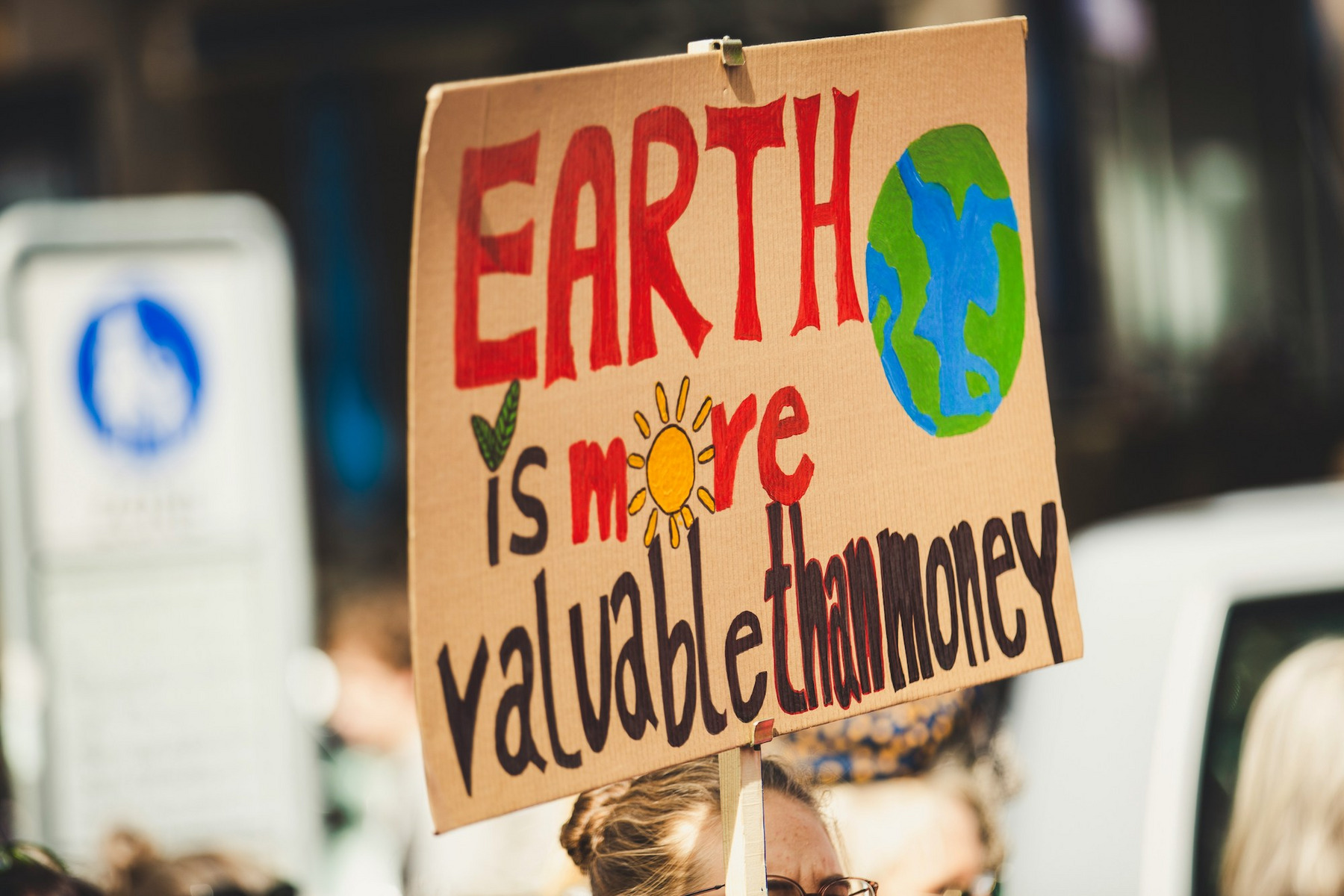 Zu sehen ist ein Schild mit der Aufschrift „Earth is more valuable than money“