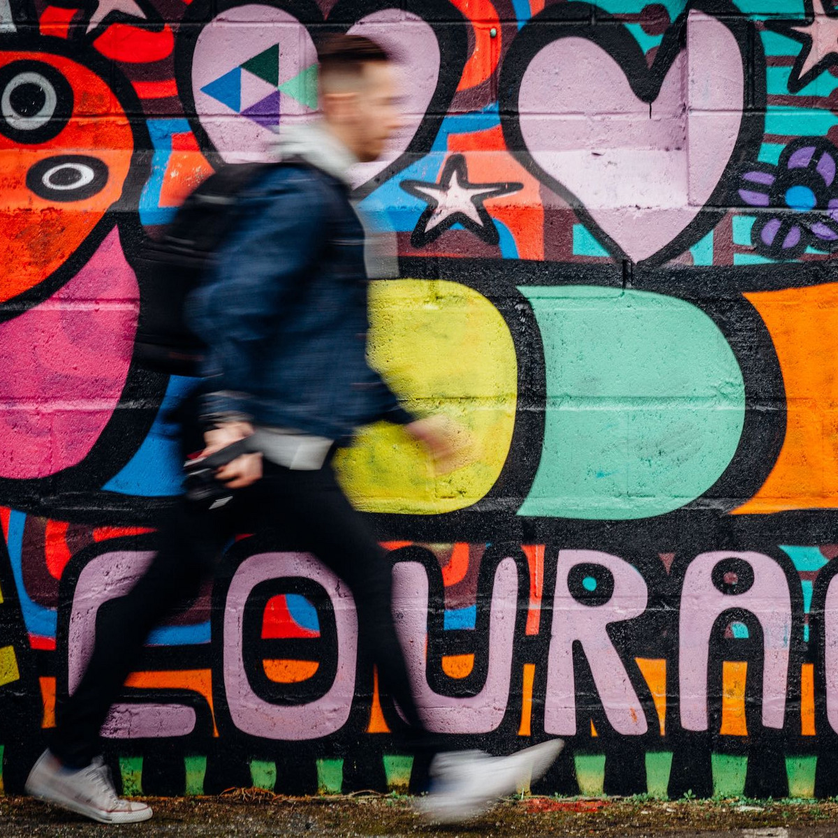 Eine Person läuft an einer Wand vorbei, auf der "Courage" steht